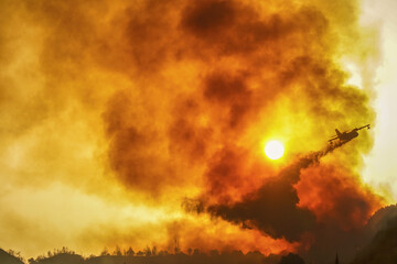 A firefighting plane releases its load of water as it tries to extinguish a fire