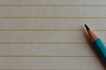 a sharply sharpened pencil lies on lined paper. copy space - Powered by Adobe