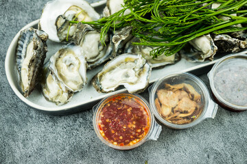 Set of spicy fresh oyster Thai style , fresh oyster, spicy sauce, deep-fried onion and fresh Acacia pennata.
