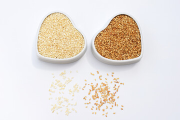 Sesame seeds in ceramic bowls of heart shape - white raw unroasted and second roasted sesame seeds 