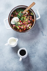 Serving pan with okroshka or russian cold soup with kvass, flatlay over light-blue stone background, vertical shot with space