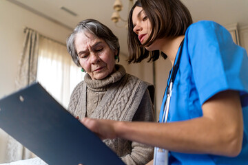 A young nurse takes care of an elderly 80-year-old woman at home