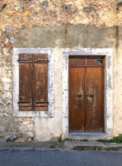 Wooden door and window blinds on old façade in Kastelli Fournis, Crete, Greece