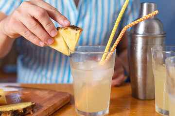 The bartender prepares a cocktail at home. Step six: decorate the cocktail with a pineapple wedge