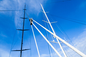 Obraz premium Masts of sailing yachts without sails with anchoring ropes. View from below.