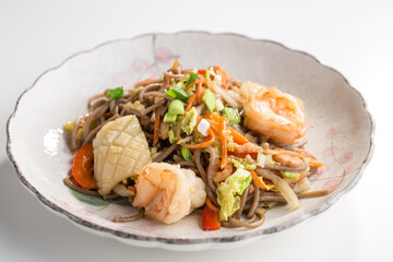 Japanese buckwheat soba noodles with shrimp and squid isolated on white background