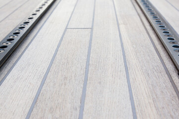 Part of the teak deck of a sailing yacht with fasteners on it.