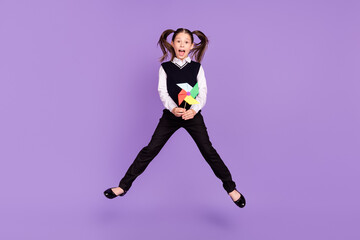 Fototapeta na wymiar Photo of nice glad schoolkid pupil girl jump hold wind mill toy wear uniform isolated violet color background