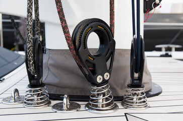 Part of the mast and hull of a sailing yacht, with multi-colored ropes, rollers and hinges for...