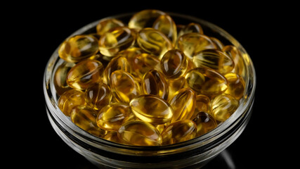 Gold oil capsules Omega 3 on black background. Supplement vitamins in softgel capsules. Golden Omega 3 pills. Dietary supplement