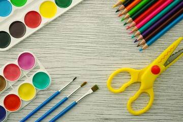 School supplies: colored pencils, watercolors, brushes, felt-tip pens. Background with painter art tools. Flat lay, copy space.	