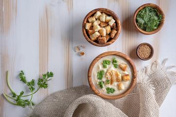 White cauliflower cream soup with croutons on wooden table with copy space