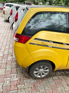 A Yellow Car Parked Along With Other Cars In A Parking Lot 