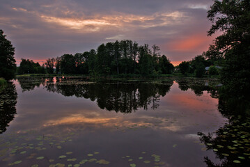 Colorful, cloudy sunset over pond in Białowieski Park Narodowy, located in Białowieża, Poland.