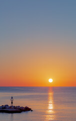 Sunrise over the sea, view of the pier and lighthouse, vertical view.