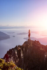 Adventurous Caucasian Woman Hiking on top of a Rocky Mountain Cliff. Dramatic Sunset Art Render. Mnt Brunswick Hike, North of Vancouver, British Columbia, Canada.