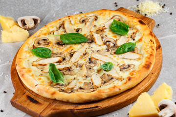 pizza with chicken and mushrooms and green basil close-up on a background of parchment and cheese