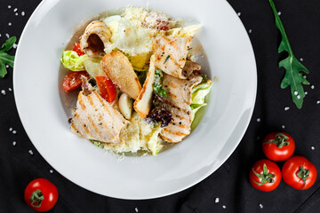 caesar with chicken in a white plate on a dark background