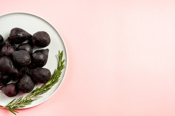 Fresh ripe figs in a plate. Beautiful blue violet fruit on pastel pink background. Healthy Mediterranean fig fruit. Copy space for text. Top view. Vegan concept