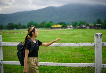 Side view point of young women backpacker walking along the fence in countryside area , chiang  mai north of thailand , freedom , calm and inspiration concept