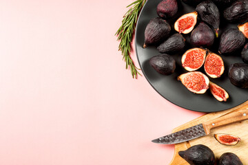 Fresh ripe figs in a plate. Beautiful blue violet fruit on pastel pink background. Healthy Mediterranean fig fruit. Copy space for text. Top view. Vegan concept