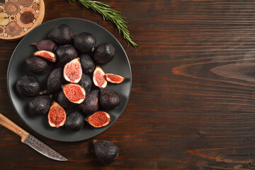 Delicious ripe figs served on dark wooden board, flat lay. Tasty figs freshly cut in half. Healthy food concept. Top view.