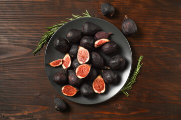 Delicious ripe figs served on dark wooden board, flat lay. Tasty figs freshly cut in half. Healthy food concept. Top view.