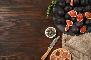 Delicious ripe figs served on dark wooden board, flat lay. Tasty figs freshly cut in half. Healthy food concept. Top view.