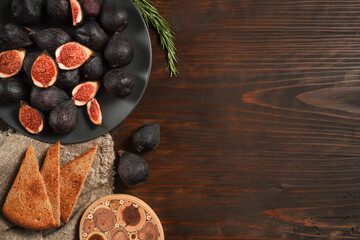 Obraz na płótnie Canvas Delicious ripe figs, spice and bread served on dark wooden board, flat lay. Tasty figs freshly cut in half. Healthy food concept. Top view.
