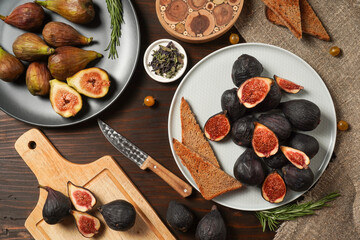 Delicious ripe figs, spice and bread served on dark wooden board, flat lay. Tasty figs freshly cut in half. Healthy food concept. Top view.