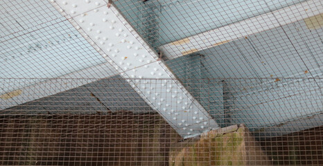 Underside of metal railway bridge showing nuts and bolts and pigeon netting