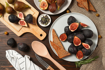 Delicious ripe figs, spice and bread served on dark wooden board, flat lay. Tasty figs freshly cut in half. Healthy food concept. Top view.
