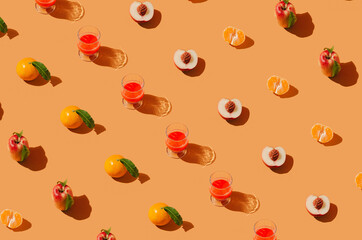 Creative summer pattern with fresh fruits and glass of drink on pastel orange background. Colorful sunlit flat lay.