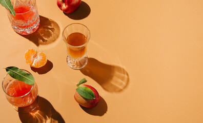 Summer day shadow ambient with glasses and fruits on pastel orange background. Authentic peachy idea.