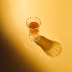 Authentic sunlit summer idea with a glass of drink on pastel orange background. Creative minimal concept.