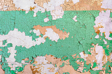 Peeling green and brown paint on old wall forms abstract textured background