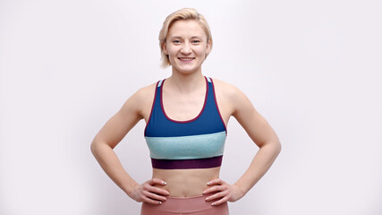 Sporty girl dressed in activewear posing for the camera. Hands on her waist. Isolated over white background studio shot, Concept of losing weight. Diet and healthy lifestyle. Women's health.