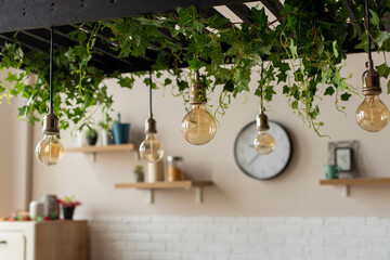 Wooden kitchen room with dining table and bar chairs, parquet floor. Kitchen open space room with bookshelf, wooden light furniture. Bulb light.
