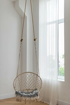Hanging home rope swing in a Scandinavian interior. The concept of home life, hugge, home comfort.