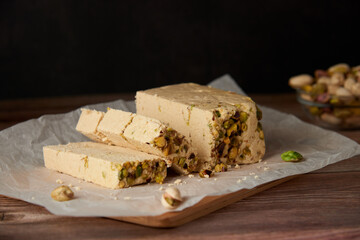 Organic halva with pistachios on a wooden surface. Traditional middle eastern sweets. Jewish, turkish, arabic oriental national dessert. Turkish delight concept. Natural vegan product. Copy space.