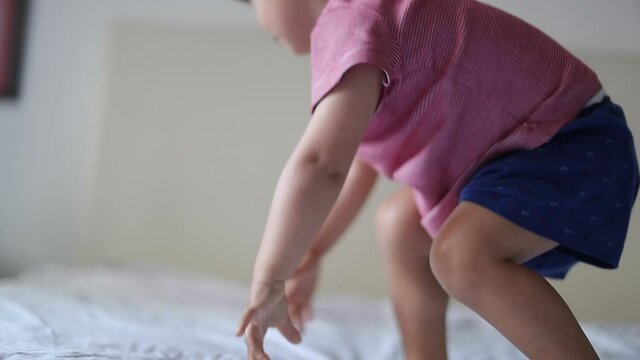 Child jumping into bed. Playful Baby boy getting up and jumps
