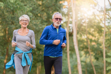 Smiling senior couple jogging in the park. Sports activities for elderly people.