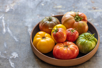 Heirloom tomatoes in black bowl on rustic metal surface