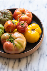 Heirloom tomatoes in black bowl on marble counter