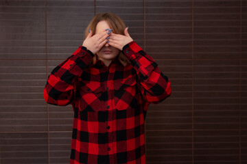 A young girl covers her face and eyes with her hands. Women's emotions.