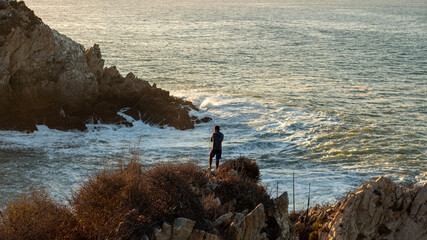 Hombre de pie en una roca sobre el mar