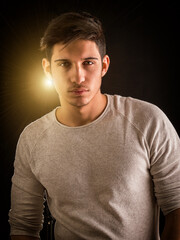 Fit handsome young man standing confident in casual clothes with light behind him