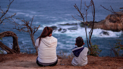 Madre e hijo sentados viendo el mar