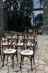 brown wooden chairs with crisscross back. White pillows on chairs and envelopes with white rose petals. against the backdrop of nature on a stone floor. holiday concept.