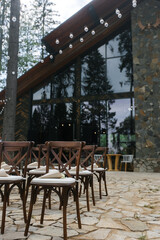 brown wooden chairs with cross-backs. Wedding decoration in nature, against the backdrop of the river and pine trees. natural wedding decor in a rustic style. holiday concept.